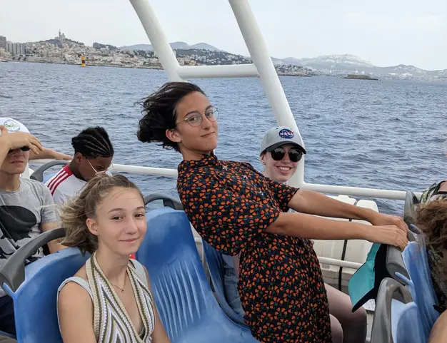 Trois participant et participantes Tandem sur la navette vers les îles du Frioul avec la bonne mère en arrière plan